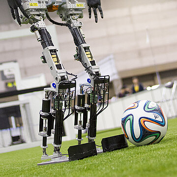 ein Robot mit dem Ball auf dem Fussballfeld 